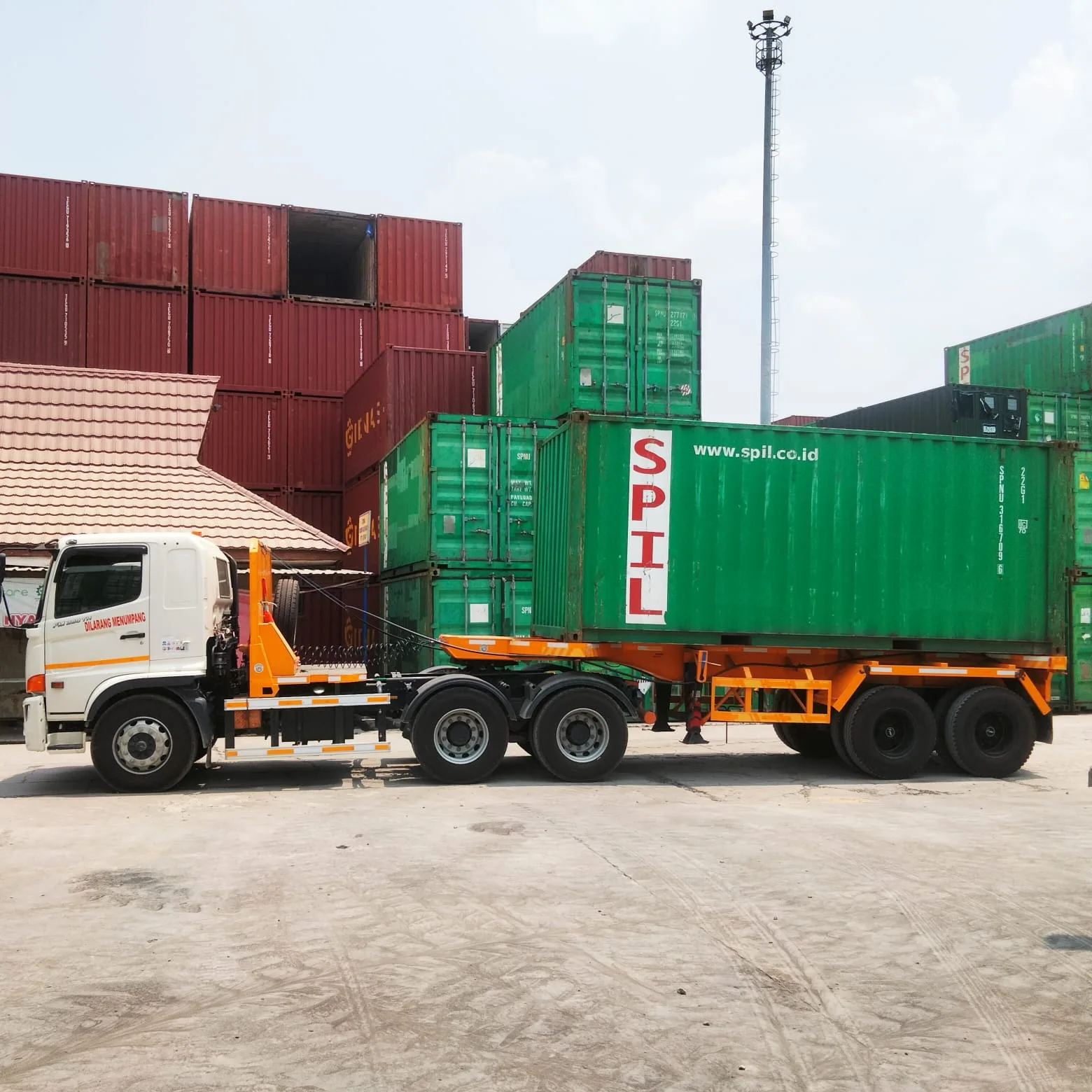 Tampak samping trailer dengan muatan peti kemas.